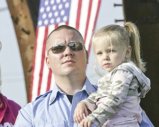 William D. Lewis | The Vindicator Austintown Fire Fighter Nick Reed holds his daughter Ariana, 3, during a Sunday observance of the 9/11 attacks at the Austintown 9/11 Memorial Park. Hundreds of area residents and representatives from many fire departments where on hand for the event.