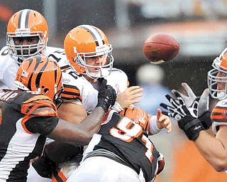 Cleveland Browns quarterback Colt McCoy throws an incomplete pass while pressured by Cincinnati Bengals defensive end Carlos Dunlap, front left, and Robert Geathers in an NFL football game on Sunday, Sept. 11, 2011, in Cleveland. Reaching for the ball is Cleveland Browns center Alex Mack. (AP Photo/David Richard)