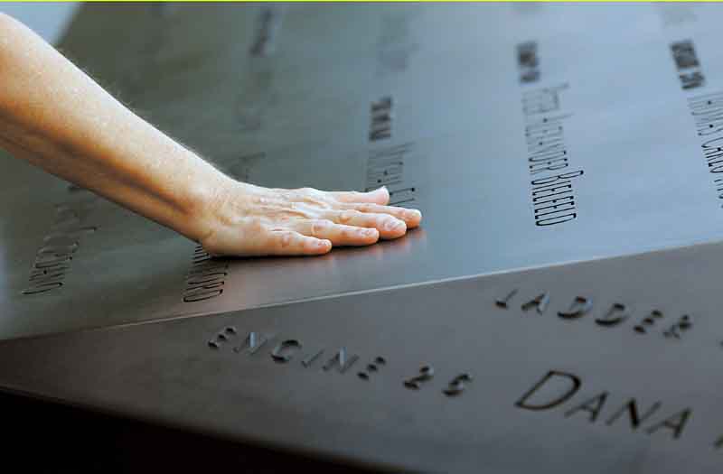 A woman places her hand on a name etched in the wall of one of the pools at the 9/11 memorial plaza in the World Trade Center site in New York Monday, Sept. 12, 2011, on the first day that the memorial was opened to the public. (AP Photo/Mike Segar, Pool)