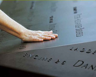 A woman places her hand on a name etched in the wall of one of the pools at the 9/11 memorial plaza in the World Trade Center site in New York Monday, Sept. 12, 2011, on the first day that the memorial was opened to the public. (AP Photo/Mike Segar, Pool)