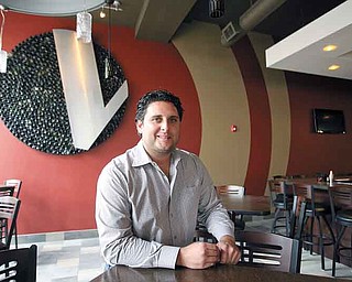 Dominic L. Gatta III, a co-owner of the Federal Building, said downtown living is now catching on in Youngstown. His company invested $2.5 million in the building on West Federal Street. Above, he sits in the V2 Wine Bar Trattoria restaurant on the building’s first floor. It is expected to open this month. Apartments occupy the upper floors.