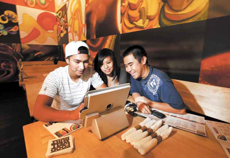 Taylor Minatogawa, right, watches his friends Reanne Lamason and Kyerin Cubos navigate the iPad ordering system at Stacked in Torrance, California on September 10, 2011.  (Liz O. Baylen/Los Angeles Times/MCT)