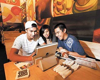 Taylor Minatogawa, right, watches his friends Reanne Lamason and Kyerin Cubos navigate the iPad ordering system at Stacked in Torrance, California on September 10, 2011. (Liz O. Baylen/Los Angeles Times/MCT)