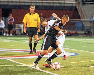 Austintown Fitch senior Mike Shaffer, white uniform, battles for possession against Canfield senior Tony ElHayek during the first half of Thursday’s boys soccer game in Austintown. The Cardinals won the AAC contest, 2-1.
