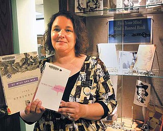 Amy Neral, the Hubbard Public Library’s teen librarian, holds “Of Mice and Men” and “Animal Farm,” two books that have been banned or challenged in several libraries and schools over the years. The library will join the country for a banned-book reading from 6 to 8 p.m. Saturday in Harding Park.