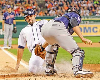 Detroit Tigers' Alex Avila safely slides under the tag of Cleveland Indians catcher Lou Marson on teammate Ryan Raburn's triple during the second inning of a baseball game, Monday, Sept. 26, 2011, in Detroit. (AP Photo/Carlos Osorio)