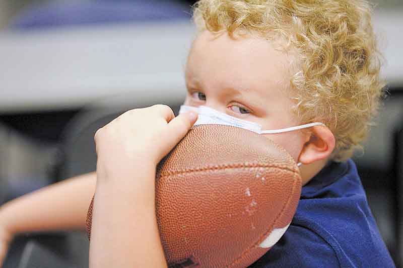 Mickey Howard, 6, a patient at Akron Children’s Hospital Mahoning Valley, waits to have his football autographed by Jim Harbaugh, head coach of the 49ers. Harbaugh and several players visited the hospital Monday.
