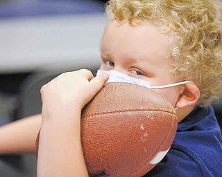 Mickey Howard, 6, a patient at Akron Children’s Hospital Mahoning Valley, waits to have his football autographed by Jim Harbaugh, head coach of the 49ers. Harbaugh and several players visited the hospital Monday.