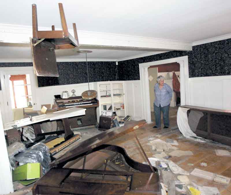 A piano chair hangs from the ceiling in the home of Martha Gordon as she looks through her home destroyed during the flood in the aftermath of Hurricane Irene, Monday, Sept. 26, 2011, in Wayne, N.J. The chair, which was on top of a piano, was lodged into the ceiling when the Ramapo River crested sending floodwaters into the residence. Gordon, who has lived at the house for 50 years, says she has given up and will be tearing the house and moving to Maine. She has talked to FEMA, but doesn't expect any quick relief aid. (AP Photo/Julio Cortez)