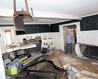 A piano chair hangs from the ceiling in the home of Martha Gordon as she looks through her home destroyed during the flood in the aftermath of Hurricane Irene, Monday, Sept. 26, 2011, in Wayne, N.J. The chair, which was on top of a piano, was lodged into the ceiling when the Ramapo River crested sending floodwaters into the residence. Gordon, who has lived at the house for 50 years, says she has given up and will be tearing the house and moving to Maine. She has talked to FEMA, but doesn't expect any quick relief aid. (AP Photo/Julio Cortez)