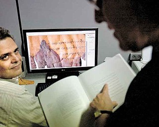 Photographer Yair Medina, left, shows Pnina Shor, right, curator and Head of Dead Sea Scrolls Project at the Israel Antiquities Authority, IAA, scanned fragments of the Dead Sea Scrolls on a computer screen, at the IAA offices at the Israel Museum in Jerusalem, Monday, Sept. 26, 2011. Two thousand years after they were written and decades after they were found in desert caves, some of the world-famous Dead Sea Scrolls are available online. Israel's national museum and the international web giant Google are behind the project, which saw five scrolls go online Monday. (AP Photo/Sebastian Scheiner)