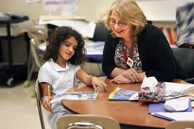 Cerise Mills, a third grade teacher at Taft Elementary School in Youngstown, works with third grader Delaney Niemczura on her lessons.