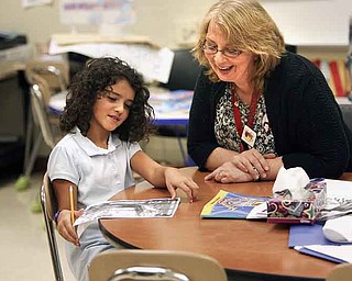 Cerise Mills, a third grade teacher at Taft Elementary School in Youngstown, works with third grader Delaney Niemczura on her lessons.