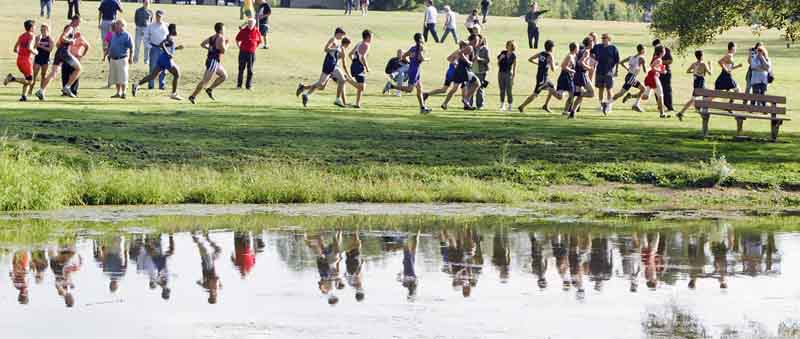 Runners are refl ected in Yeager’s Pond during Tuesday’s Mahoning County boys cross country meet at Austintown Park.