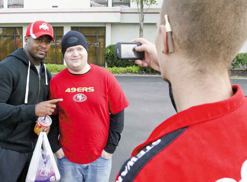 Donte Whitner of the San Francisco 49ers poses with fan Andrew Berg of Bessemer, Pa., while Alex Reece of Boardman snaps a photo outside the Holiday Inn in Boardman. The team has been in the area since Monday.