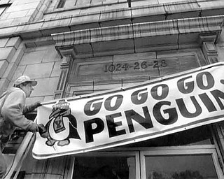 12/12/91 - Doug Oster.Go Penguins: Mark Brown, owner of Impact Signs in Youngstown, puts a "Go Penguins" sign up in front of the old Wards Bakery on Mahoning. The sign was bought by Paul Mahin of Postal Mail-Sort Inc. and Terry Thomas of special busing. The signs are available from impact for $49.95.