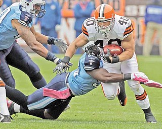 Cleveland Browns running back Peyton Hillis runs through a tackle by Tennessee Titans outside linebacker Akeem Ayers (56) as defensive end Derrick Morgan, left, moves in in the first quarter of an NFL football game Sunday, Oct. 2, 2011, in Cleveland. (AP Photo/Mark Duncan)