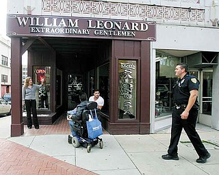Lisa Reali, owner of William Leonard’s barber and beauty shop, waves at patrolman Michael Cox as he walks his downtown beat. The Youngstown Police Department began walking the daytime downtown beat last week.