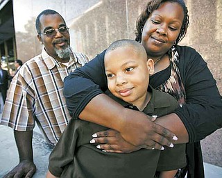 Terrel Hall, 8, is hugged by his mother Melanie Hall as his father Terrence Hall Sr. looks on after a court proceeding at the Stanley Mosk Courthouse in Los Angeles, California, July 18, 2011. The family sued the manufacturer of a medical device used for circumcision and signed a $4.6 million settlement. (Al Seib/Los Angeles Times/MCT)