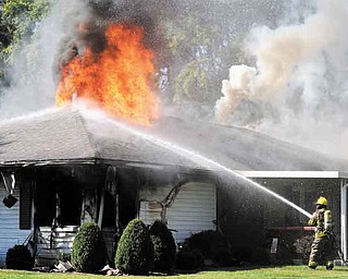 A firefighter from the Chillicothe Fire Department sprays water on a fire which broke out during a standoff with police at a home in Brewer Heights area of Chillicothe, Ohio on Saturday, Oct. 8, 2011. (AP Photo/The Chillicothe Gazette, Heather Cory)
