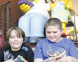 Homer, Marge and Maggie Simpson watch over Solomon Kennedy, 8, of Youngstown, and Jay Dulin, 11, of Austintown, as they look at comic books Saturday during Lawn-Con in the yard of local artist Chris Yambar.