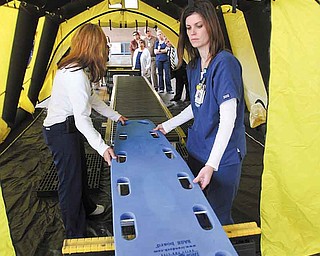 Humility of Mary Health Partners conducted orientation sessions about a decontamination unit for senior leadership in St. Elizabeth Health Centers in Youngstown and Boardman and at St. Joseph Health Center in Warren on Monday. Here St. Elizabeth registered nurses, Brenda Luchs, left, and Amanda Lencyk, demonstrate how nonambulatory patients are moved through a decontamination tent.