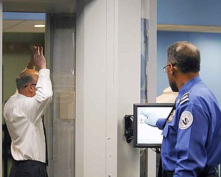 The new Advanced Imaging Technology machine at Youngstown-Warren Regional Airport in Vienna, which is equipped with automated target-recognition software, eliminates passenger-specific images and detects metallic or nonmetallic items, but does not show what those items look like. Rickey Jones, without shoes or belt and with his arms in the air, demonstrates how passengers will go through the AIT machine while Ron Warren of the Transportation Security Administration tests the equipment.