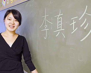 Zhen Zhen Li, a 26-year-old Chinese teacher, stands next to her name spelled out in Chinese. Li will teach 350 students from both the elementary school and the middle school for the next three years as part of a district initiative of teaching foreign languages at a younger age.