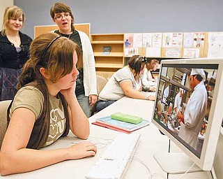 Seniors Zoella Camelli and Leah Yochman, both from Jackson-Milton, watch as team member Elizabeth Blythe from South Range puts finishing touches on the 30-second spot on the culinary arts program at Mahoning County Career and Technical Center.