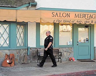 A Seal Beach police officer walks in front of the site where eight people were killed and one was wounded Wednesday in a shooting at Salon Meritage in Seal Beach, Calif., Thursday, Oct. 13, 2011. (AP Photo/Chris Carlson)