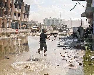 A Libyan revolutionary fighter fires with his machine gun while attacking pro-Gadhafi forces in downtown Sirte, Libya, Friday, Oct. 14, 2011. Revolutionary forces pounded Moammar Gadhafi's supporters holed up in two neighborhoods with rocket and machine-gun fire Friday in Sirte, but the loyalists showed no sign of giving up in the fugitive leader's hometown. (AP Photo/Manu Brabo)