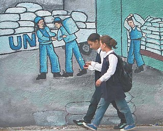 Palestinian schoolgirls walk past graffiti on a wall depicting UN humanitarian-aid supplies in Gaza City on Monday. Palestinians became full members of the U.N. cultural and educational agency Monday, in a highly divisive move that the United States and other opponents say could harm renewed Mideast peace efforts.