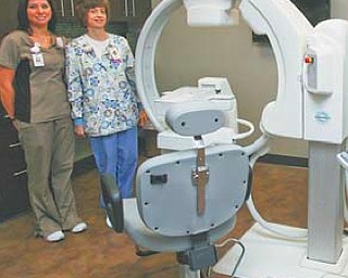 Ami Setterberg, left, and Lisa Hughes stand beside the Luma Gem Gamma Camera during a tour of the new $8 million center. The camera is an example of the state-of-the-art technology installed in the center.