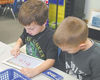 North Jackson kindergartners Tommy Derrow, 5, and Jack Pittman, 6, practice writing words on an iPad. Using a federal grant, the district began implementing the digital tablets into its curriculum this month.