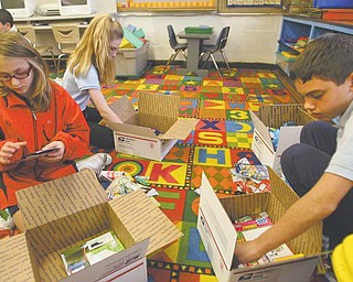 St. Joseph and Immaculate Heart of Mary sixth-graders Meg Welsh, left, Katie McHugh and Joey Jadue pack boxes with candy and supplies in honor of Veterans Day. Members of the school’s student council will send the care packages to soldiers overseas.