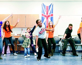 At the front of the crowd, eighth-graders Alison Rein, left, Seaven Weaver and Deborah Eshun, all 13, play Just Dance during the “Wii Play for Charity” fundraiser at Austintown Middle School. Several other students, friends and family members joined in for fun in the background Thursday evening at the event hosted by the school’s Honor Language Arts students.