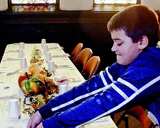 Nick Kacir, 12, a member of Boy Scout Troop 55, sets the table before the Community
Thanksgiving Dinner on Thursday at First Presbyterian Church in Youngstown.