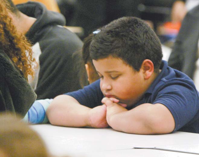 Edwin Rodriguez, a second-grader at Williamson Elementary in Youngstown, gives thanks Monday before a Thanksgiving dinner at the school. Students and their families were treated to the meal after parents attended parent-teacher conferences last week.