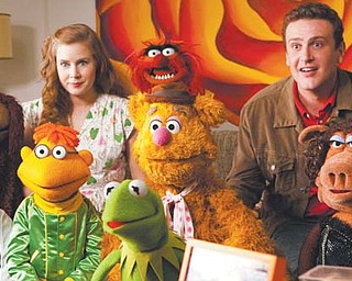 Amy Adams, left, and Jason Segel are shown with the Muppet characters in a scene from “The Muppets.”