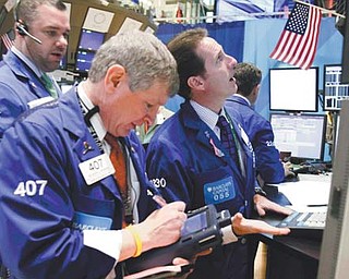 Specialist Glenn Carell, right, works at his post on the floor of the New York Stock Exchange on Monday. The collapse of talks aimed at reducing the staggering U.S. budget deficit weighed on world markets Tuesday.