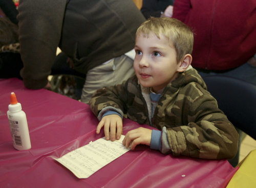 JESSICA M. KANALAS | THE VINDICATOR..Richard Yaist, 6, of Youngstown makes an ornament out of musical paper at the YSU SMARTS table which had several craft activities  during the entire holiday event in Downtown Youngstown.