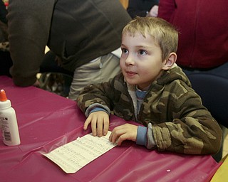 JESSICA M. KANALAS | THE VINDICATOR..Richard Yaist, 6, of Youngstown makes an ornament out of musical paper at the YSU SMARTS table which had several craft activities during the entire holiday event in Downtown Youngstown.
