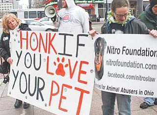 Liz Raab , left, whose dog died after being left in the care of a Youngstown kennel owner, and Dana Donnelly from Youngstown, rally near the Ohio Statehouse in Columbus for passage of a bill to allow felony charges against kennel owners who neglect or abuse animals.