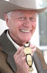 Actor Larry Hagman shows off a wrist watch elaborately decorated with the initials “J.R” inscribed on the bands.