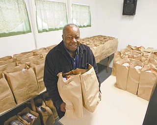 The Rev. Harold Logan, pastor of Beulah Baptist Church, 570 Sherwood Ave., Youngstown, loads two of the 200 bags of food the church's Operation Food Basket expects to distribute to needy Youngstown-area residents Saturday from 10 a.m. to 1 p.m.