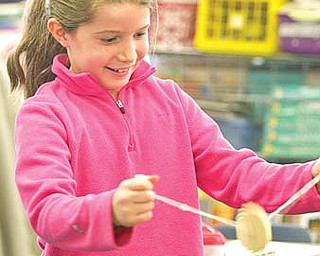 Ella Sahli of Watson Elementary School, Austintown, plays with a pioneer-era toy. It’s part of a lesson on pioneer life being presented to the students in conjunction with the Arms Family Museum of Local History.