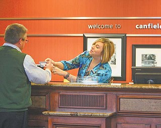 Elizabeth Caman, assistant general manager at Hampton Inn & Suites in Canfield, helps Phil Gaulin of Buffalo, N.Y. Local hotels have had higher occupancy rates this year, partially due to those coming here involved in the Utica and Marcellus shale-drilling activity.
