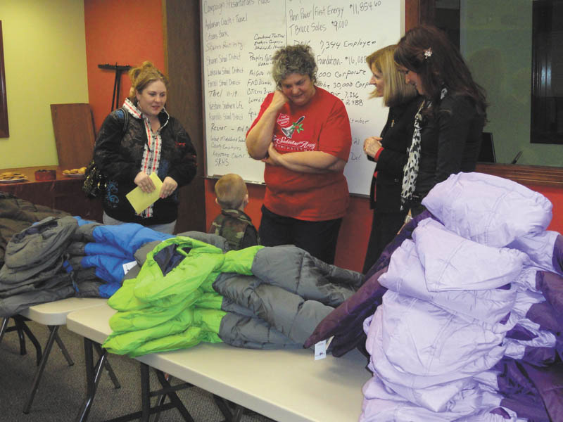 Salvation Army caseworker Marta Nagel, center, along with PNC Bank employees Debbie McMaster and Candace Turpack, right, help a young boy pick out a brand-new winter coat while his mother looks on. The coat distribution was made possible through the PNC Foundation, United Way of Mercer County and Operation Warm, whose sole mission is to provide new winter coats to children in need.