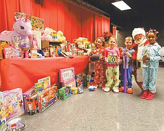 Struthers Elementary School kindergartners Hannah Johnson, left, Emma Bailey, Kamerion Nash and Tattiaunna Holmes show off the toys and food the school gathered for the Rescue Mission of the Mahoning Valley and Neighbors Helping Neighbors. The school presented the donations to Santa on Thursday morning after he arrived at the school on a firetruck.