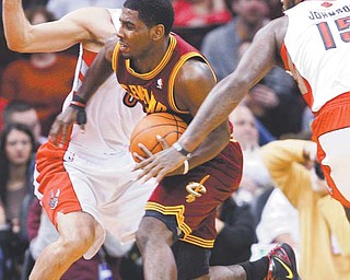 Cleveland Cavaliers’ Kyrie Irving tries to get past Toronto Raptors’ Jose Calderon, back, and Amir Johnson (15) during the first quarter of their NBA game Monday at Quicken Loans Arena in Cleveland. Irving, the No. 1 overall draft pick out of Duke, scored only six points in his NBA debut as the Cavaliers fell 104-96.